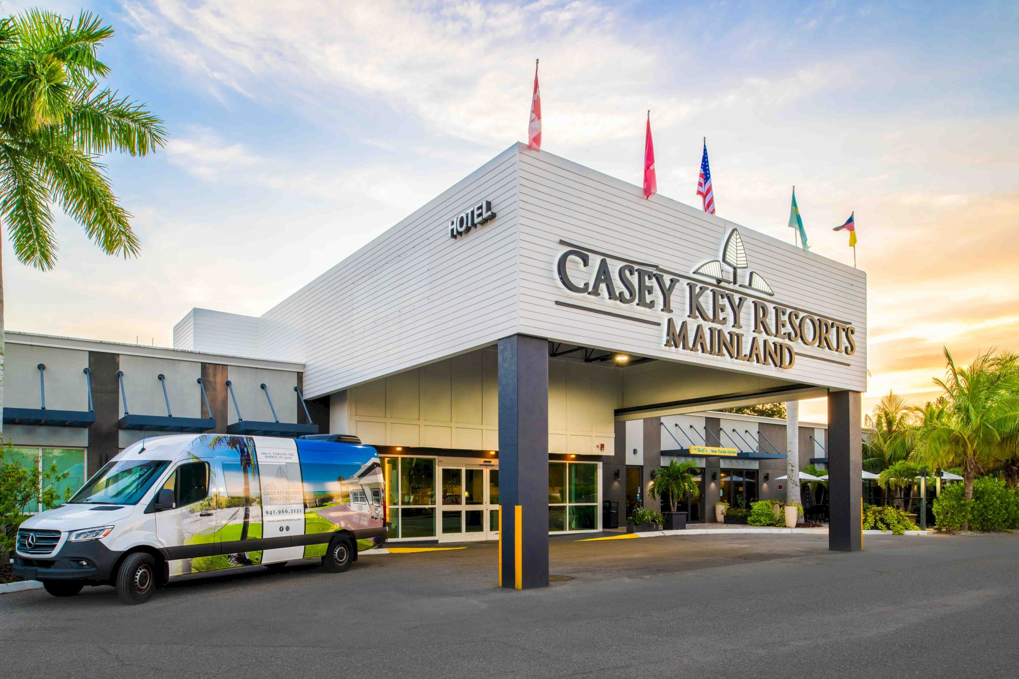 The image shows the entrance of Casey Key Resorts Mainland with a van parked outside, featuring palm trees and flags.