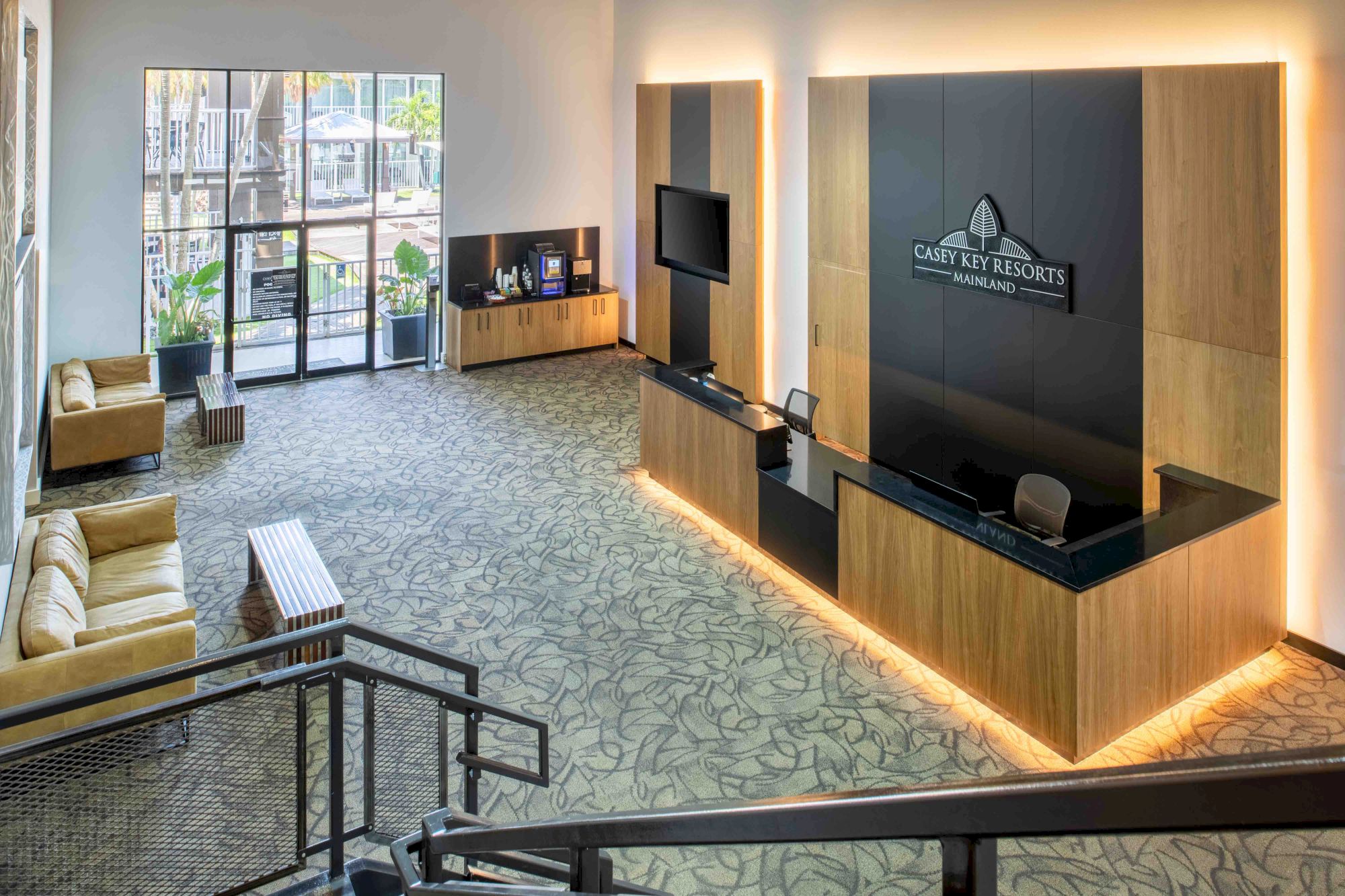 The image shows a modern hotel lobby with a reception desk, seating area, and a sign reading 