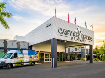The image shows the entrance of Casey Key Resorts Mainland, with a van parked in front and flags displayed on the building.